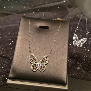 Collana con ciondolo a farfalla traforata con zirconi micro-pavé su un supporto per gioielli