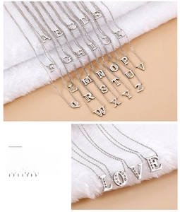 Macro shot of silver letter necklaces with sparkling cubic zirconia on white fur