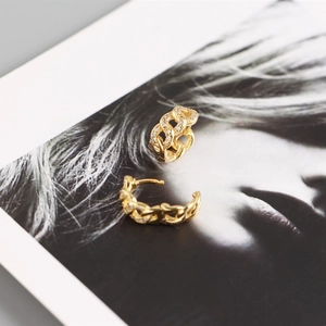 Close-up of gold chain link hoop earrings with sparkling cubic zirconia on portrait