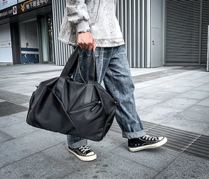Detail of a black multi-functional sports gym bag with side pockets and durable handles