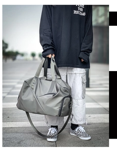 Waterproof grey duffel bag with reinforced handles shown in an outdoor street setting