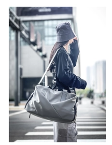 Detail of gray large-capacity travel bag with shoulder strap in urban street setting