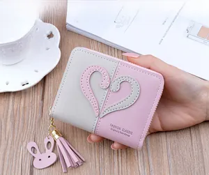 Detailed view of pink and grey contrast PU leather wallet with heart patch and tassel zipper