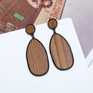 Détail de boucles d'oreilles en bois avec grain foncé et cadre métallique noir