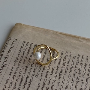 Artistic close-up of a minimalist gold ring with a white pearl on vintage newspaper