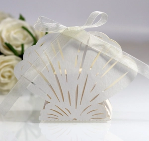 Close-up of laser-cut white shell wedding favor box with an elegant ribbon bow detail