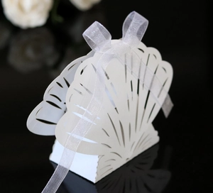 Detail of laser-cut shell candy box with white ribbon and intricate hollow pattern