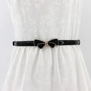 Slim black patent leather belt for women with elegant metal bow buckle on lace dress