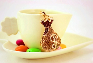 Detail of crystal rhinestone money bag keychain with dollar sign hanging on a cup
