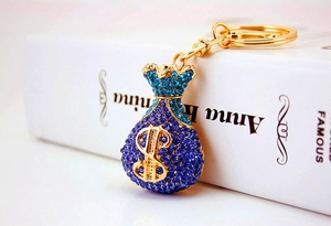 Macro shot of blue crystal money bag keychain with gold dollar sign on a white book