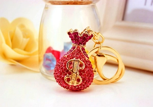 Macro shot of red rhinestone money bag keychain with gold clasp and dollar symbol