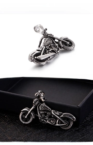 Detail of vintage silver motorcycle pendant with intricate engine and exhaust pipe textures