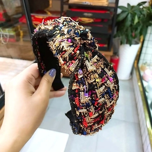 Dettaglio di cerchietto largo in tweed con ricami in fili metallici dorati e viola scuro
