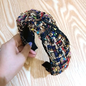 Dettaglio del cerchietto in tweed con nodo centrale e texture intrecciate multicolori vivaci