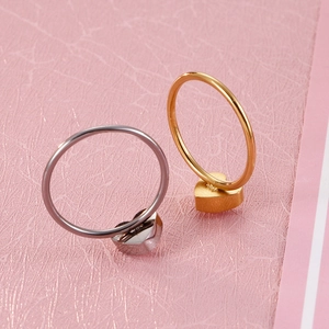 Minimalist heart zircon titanium steel rings in gold and silver on a pink background