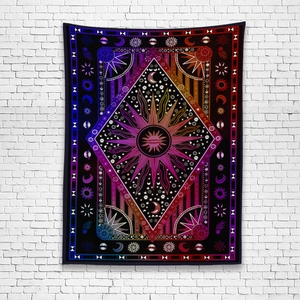 Detail of bohemian tapestry with psychedelic sun and moon design on white brick wall