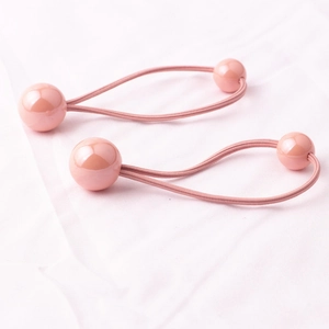 Dettaglio di elastici per capelli rosa per bambine con perle tonde su un panno morbido