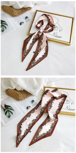 Detailed view of pink floral long silk scarf styled with magazine and home decor