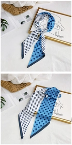 Detail of blue and white polka dot silk scarf tied on a stylish gold frame stand