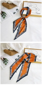 Detail of a chic orange silk scarf with dark blue floral patterns used as a hair ribbon