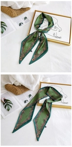Detail of a green silk scarf with brown floral patterns tied to a woven basket