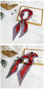 Detailed view of red and purple floral silk scarf on white fabric with gold frame