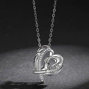 Silver heart and angel wing necklace with zircons on dark textured background