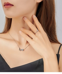 Detailed view of S925 silver bow necklace and ring set with blue gemstone on a model