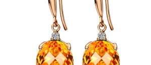 Macro detail of oval cut orange citrine earrings in rose gold setting with small diamonds