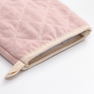 Close-up of pink quilted heat-resistant oven mitt with diamond stitching and hanging loop