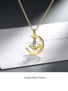 Macro shot of gold crescent moon and planet pendant with sparkling zircon micro-inlays