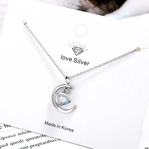 Elegant silver planet and moon pendant necklace on minimalist jewelry display card