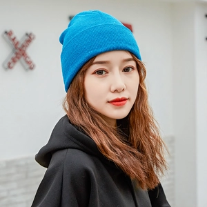 Blue knit beanie hat for women featuring a cuffed design worn by a model in a studio setting