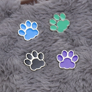 Set of four colorful cat paw enamel pins in blue, green, black and purple on fur