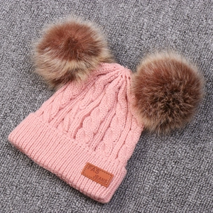 Pink cable knit winter hat for children featuring double faux fur pom poms and ear flaps
