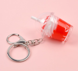 Détail d'un mini porte-clés boisson réaliste avec tourbillon rouge sur fond rose