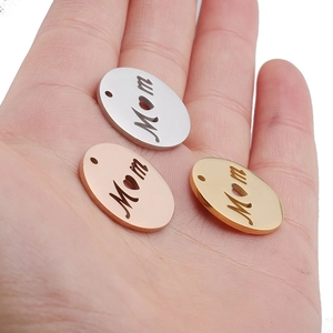 Hand holding 20mm MOM cutout circular pendants in silver, gold, and rose gold stainless steel
