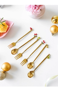 Detailed view of golden stainless steel spoons and forks with cute fruit pendants