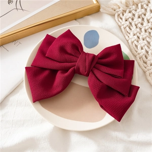 Detail of red fabric triple-layered bow spring hair clip on a decorative ceramic plate