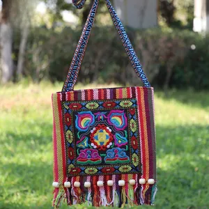 Detailed close-up of ethnic embroidered crossbody bag with colorful tassels and lotus patterns
