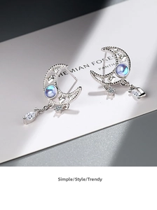 Macro shot of silver crescent moon earrings with crystal charms and moonstone inlay
