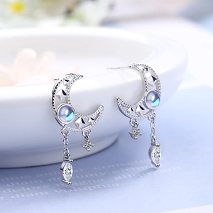 Silver crescent moon tassel earrings with opal stones and zircons on ceramic bowl