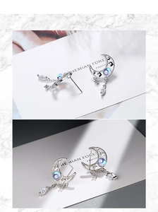 Detailed close-up of crescent moon earrings with moonstone and dangling star charms