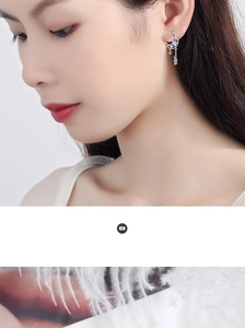 Close-up of silver crescent moon earrings with delicate chain tassels and shimmering zircons