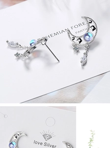 Macro shot of silver crescent moon earrings with blue moonstone and white zircons