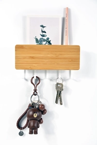 Detail of wooden wall-mounted key holder with mail slot and white hooks for entryway