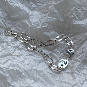 Detailed macro shot of silver chain bracelet featuring a cartoon girl and round charms
