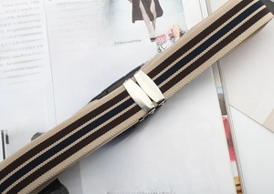 Detail of striped elastic belt with silver metal clip on a fashion magazine background