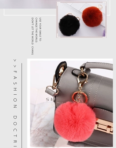 Fashionable faux rabbit fur pom pom pendant keychain on a stylish grey handbag