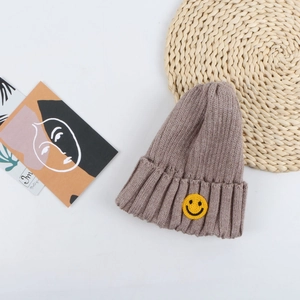 Detail view of brown knit beanie featuring a yellow smiling face embroidery patch